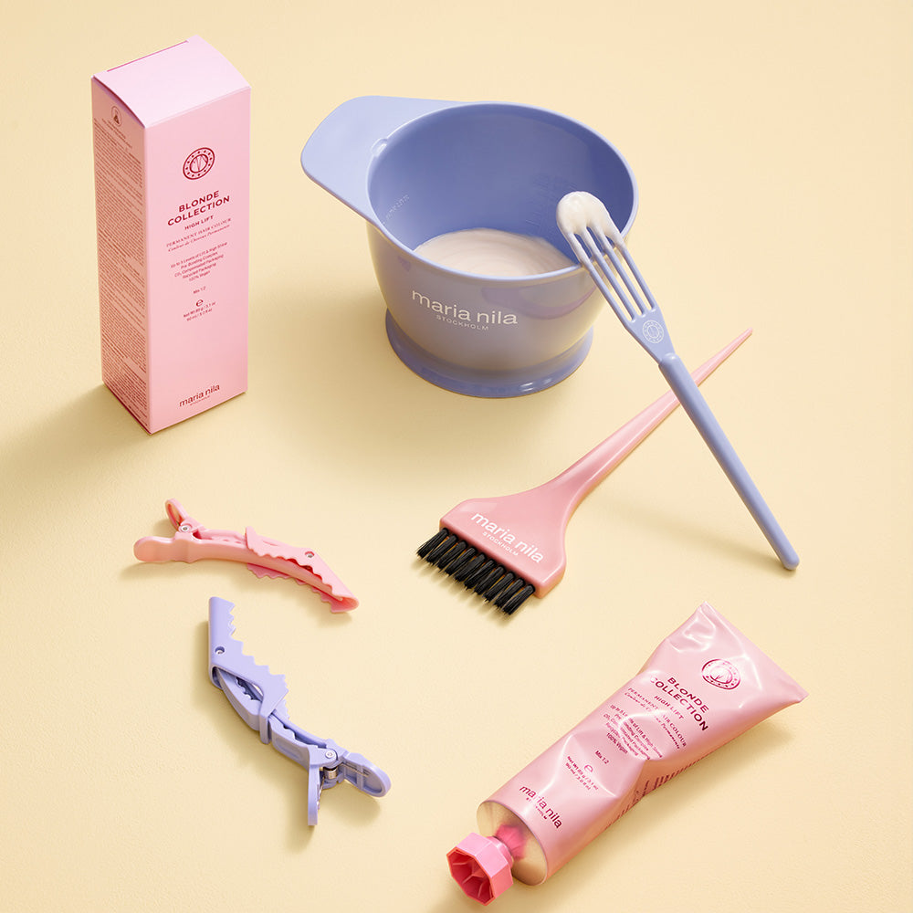 Still life image of tubes of hair color, bowl with formula and brushes on yellow background.