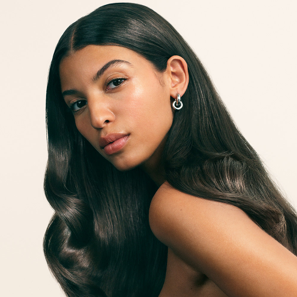 Woman with long dark glossy hair against beige background
